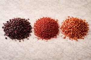 Side-by-side comparison of Urfa pepper, Aleppo pepper, and crushed red pepper flakes showing differences in color, texture, and seeds.